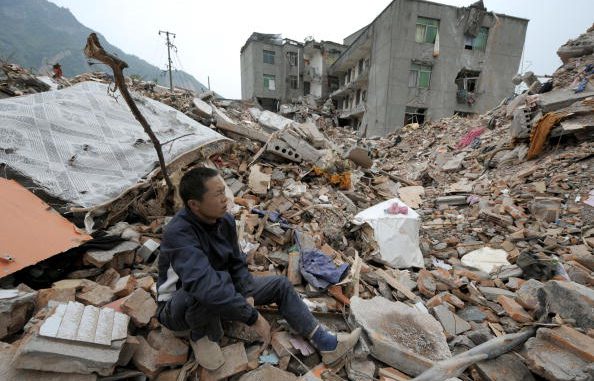 2008年汶川大地震后，幸存者坐在瓦砾堆上。据民间组织巴蜀同盟会调查，这次地震死亡人数约30万人( LIU JIN/AFP/Getty Images)