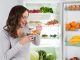 Woman Eating In Front Of Fridge