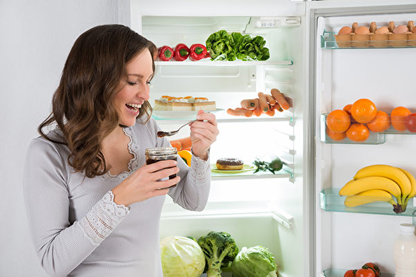 Woman Eating In Front Of Fridge