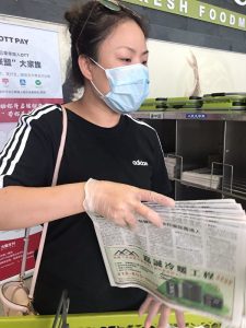 2020年7月3日，在多伦多的鸿华超市，一名30岁左右、讲普通话的女性从报架拿了一叠大纪元报纸，放进了她的菜篮。