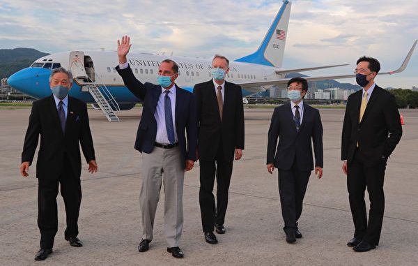 8月9日，美国卫生部长艾萨（Alex Azar）（左二）步出军机，挥手向现场人员致意。