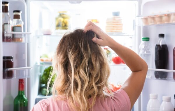 Rear,View,Of,A,Confused,Woman,Looking,In,Open,Refrigerator