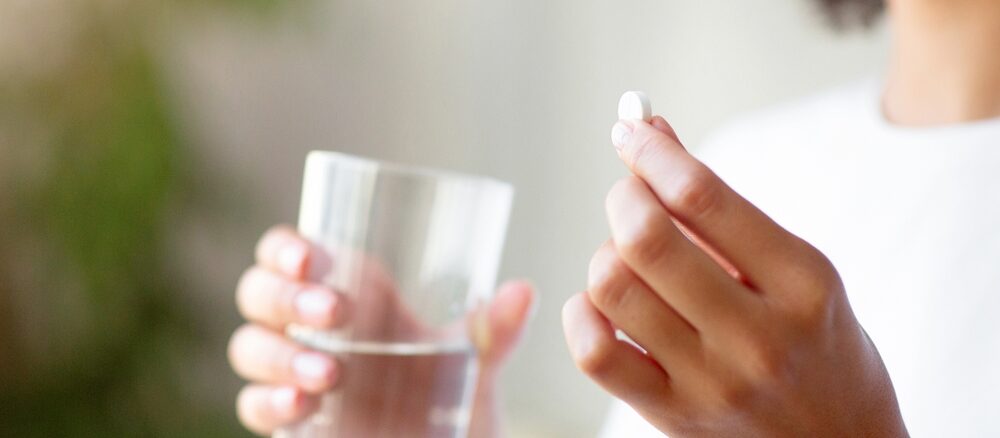 女子手拿水杯与药片