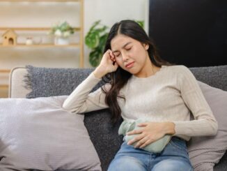 女子捂着肚子坐在沙发上